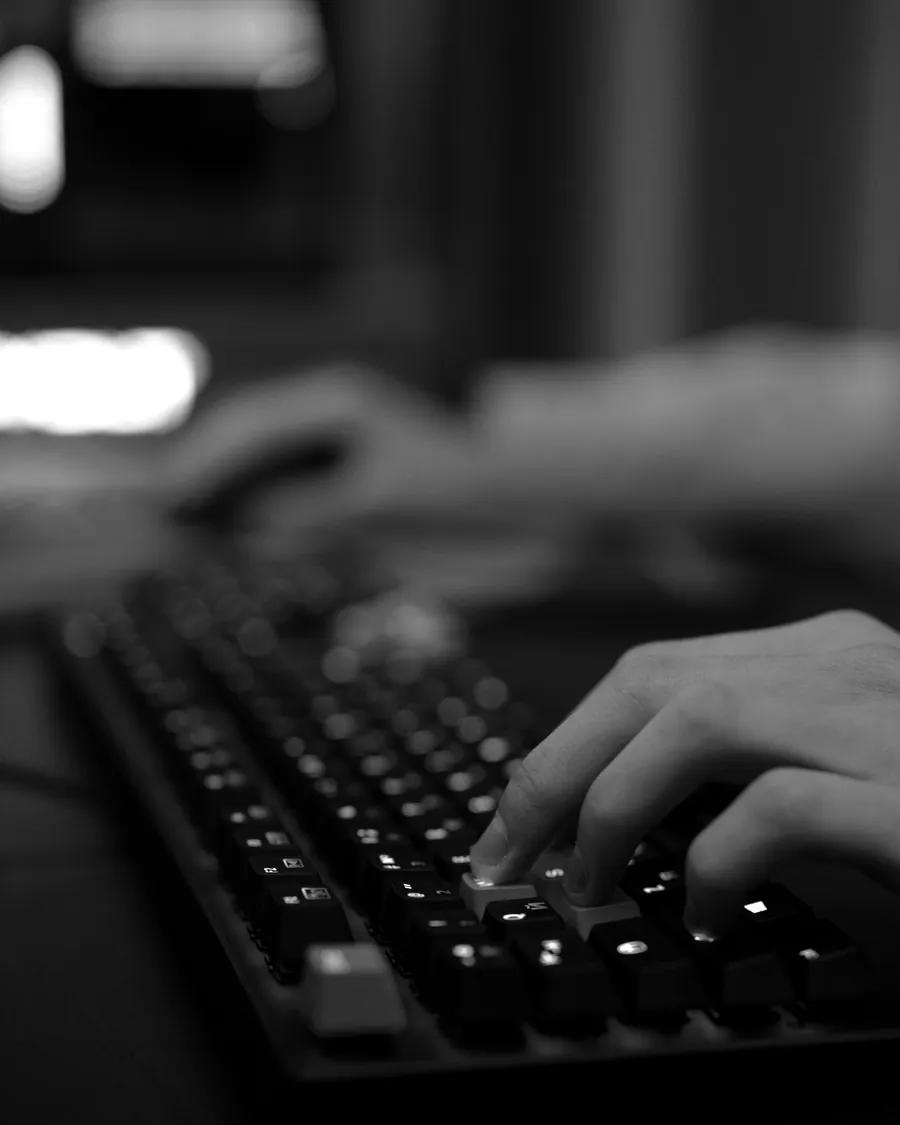 Hands on a backlit mechanical keyboard at a darkened desk.
